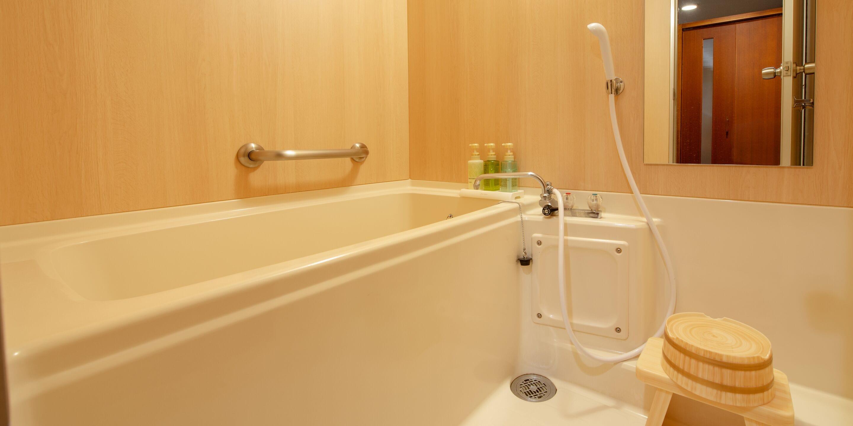 A bathroom with a bathtub, a shower, and a wooden stool.