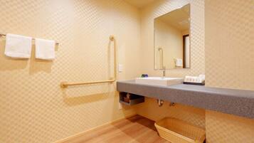 Un baño con un estampado de cuadros en la pared, un lavabo con espejo, un perchero, un asidero, una cesta y un estante pequeño con artículos de aseo.