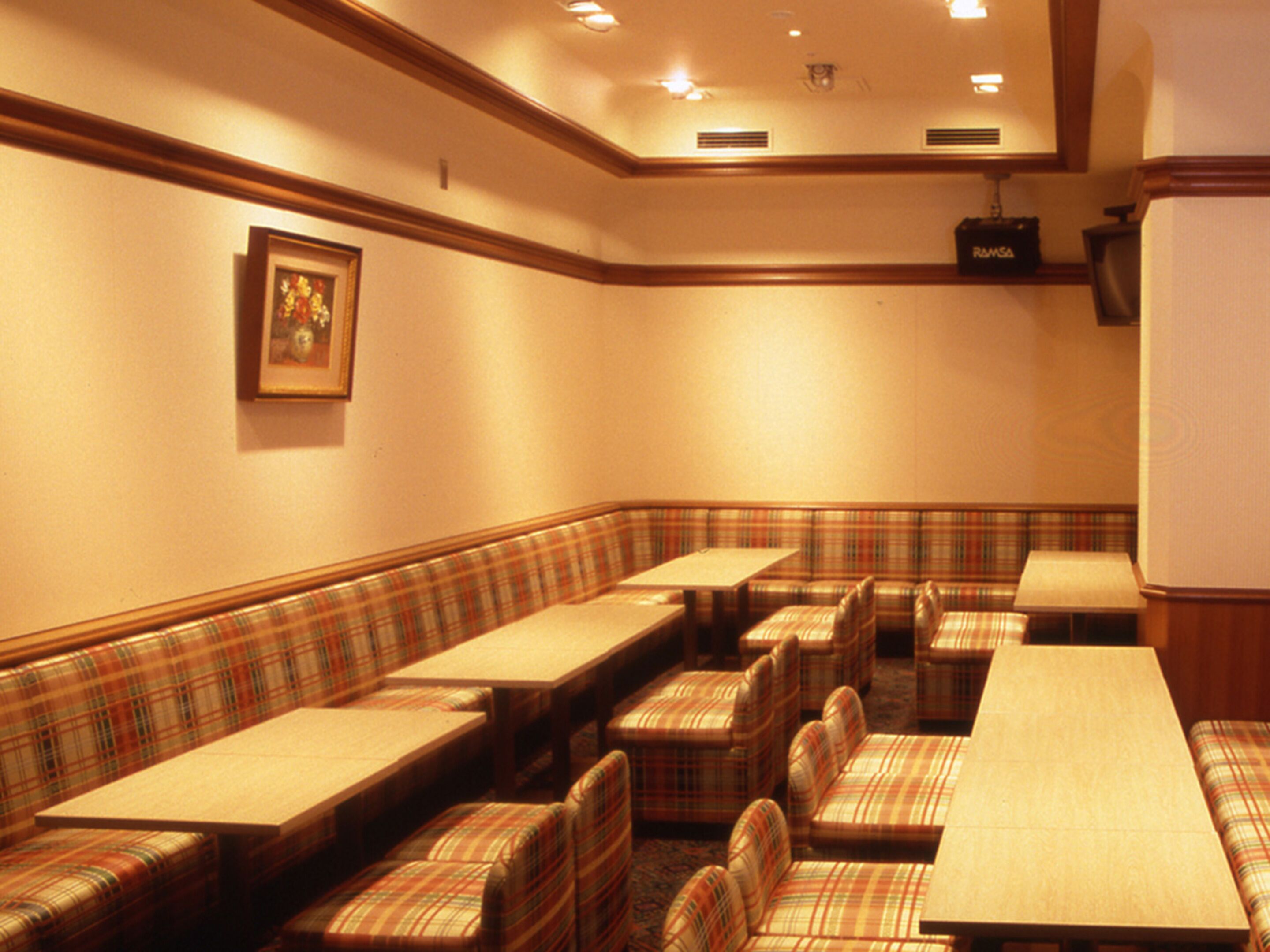 A conference room with plaid-patterned seating, a projector, and a framed picture on the wall.