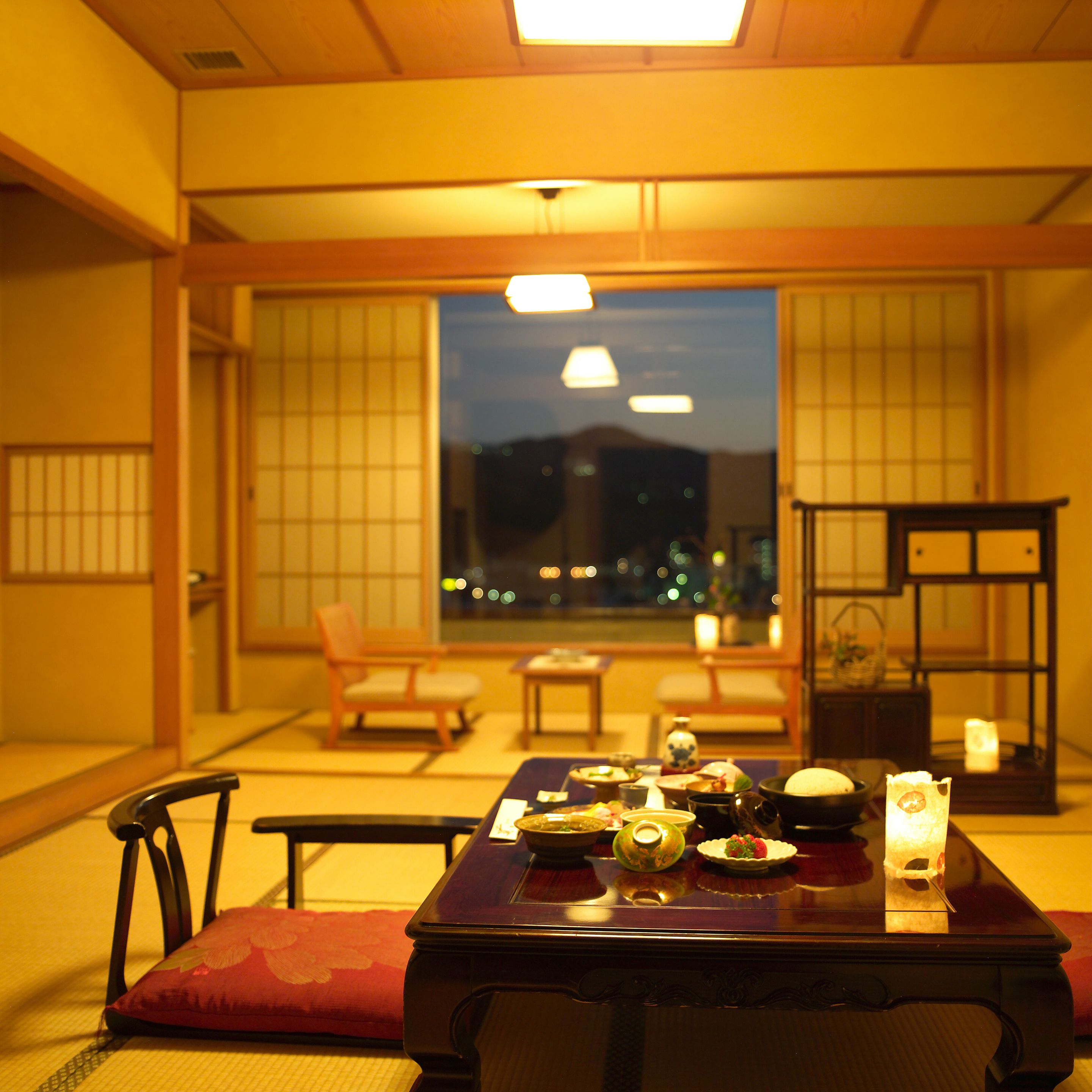 A traditional Japanese room with tatami flooring, a low table with dishes, and sliding doors.