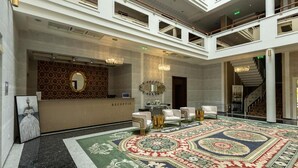 Un amplio vestíbulo con mostrador de recepción, zona de estar y una gran alfombra decorativa.