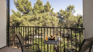 A balcony with a table set for two, featuring a fruit plate, a glass of orange juice, and a glass of water.