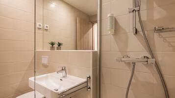 A modern bathroom with a glass-enclosed shower, a white sink, and a toilet.