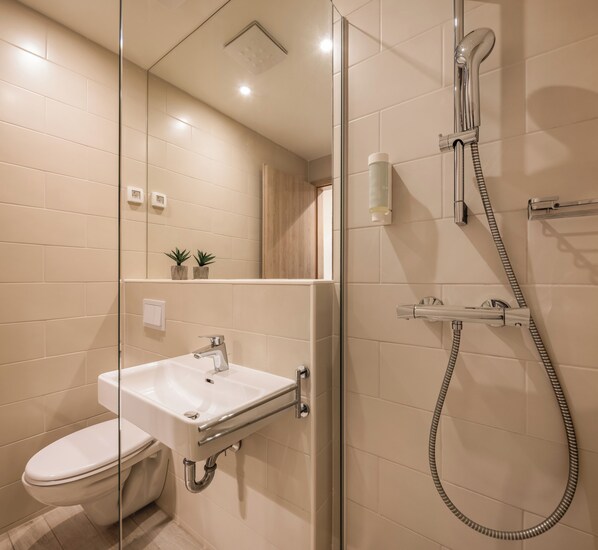 A modern bathroom with a glass-enclosed shower, a white sink, and a toilet.