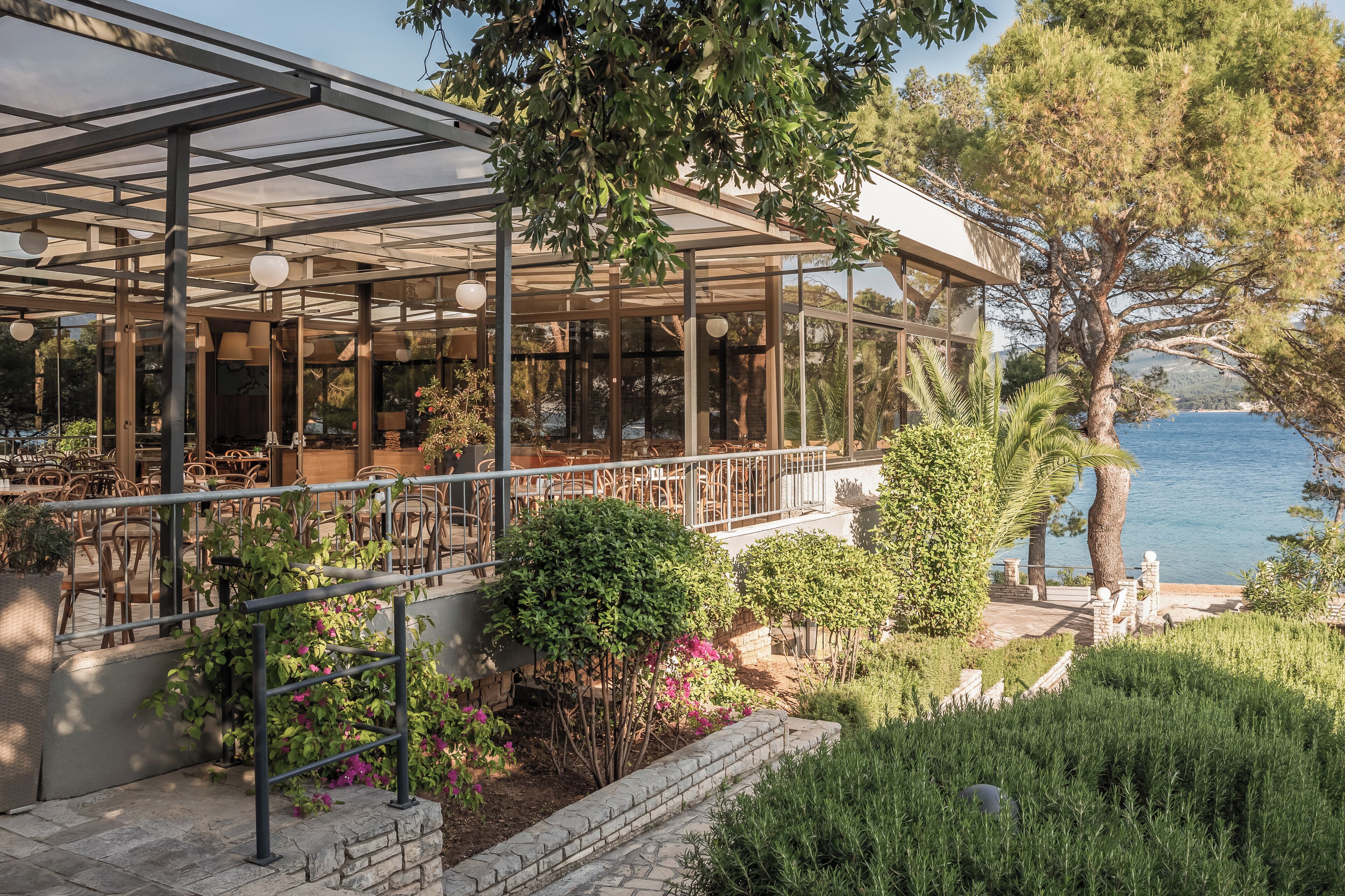 Un restaurante con terraza, un recinto de vidrio y vista al mar.