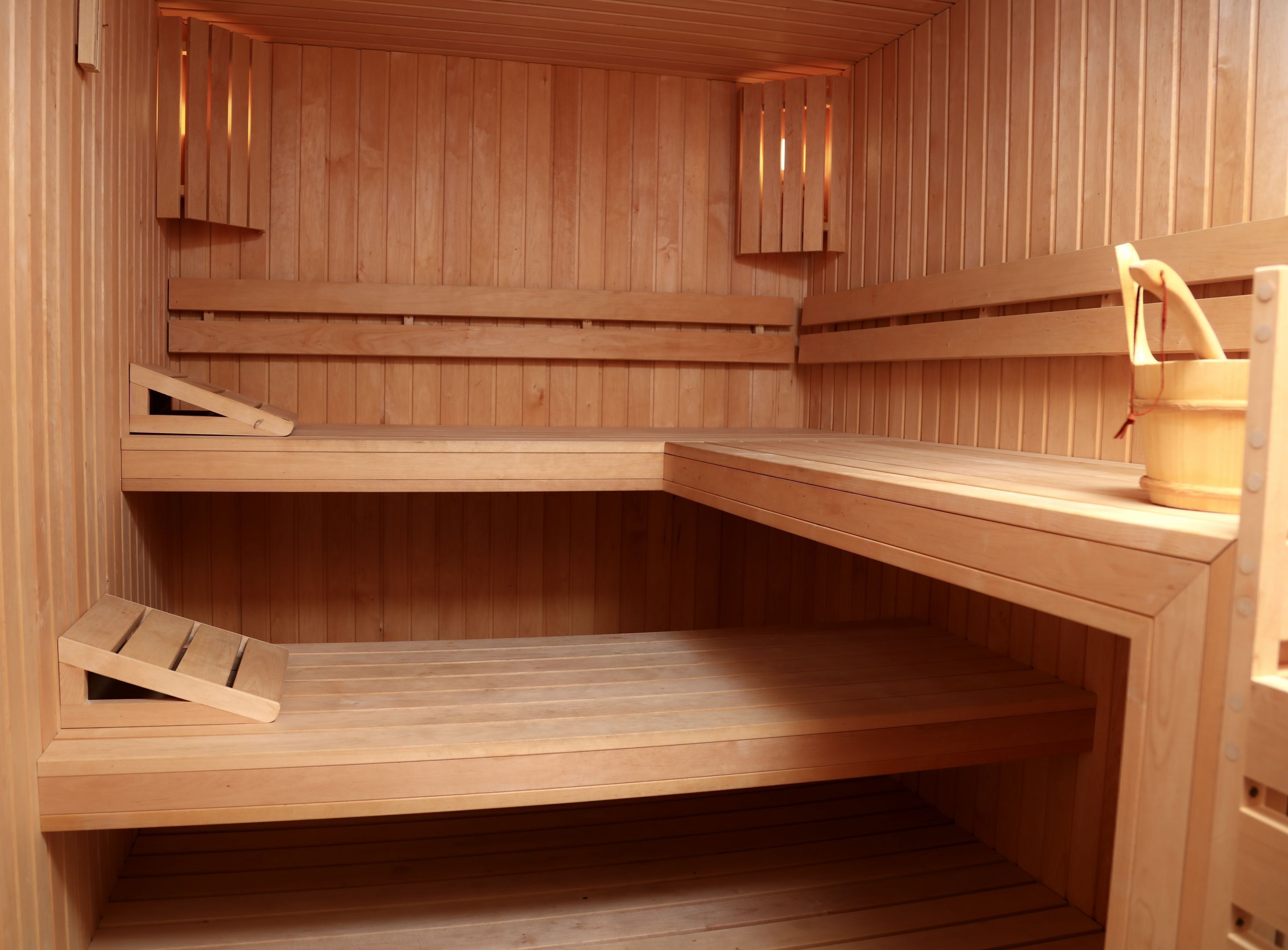 Een houten sauna met een bankje, een plank en een klein tafeltje met een handdoek.