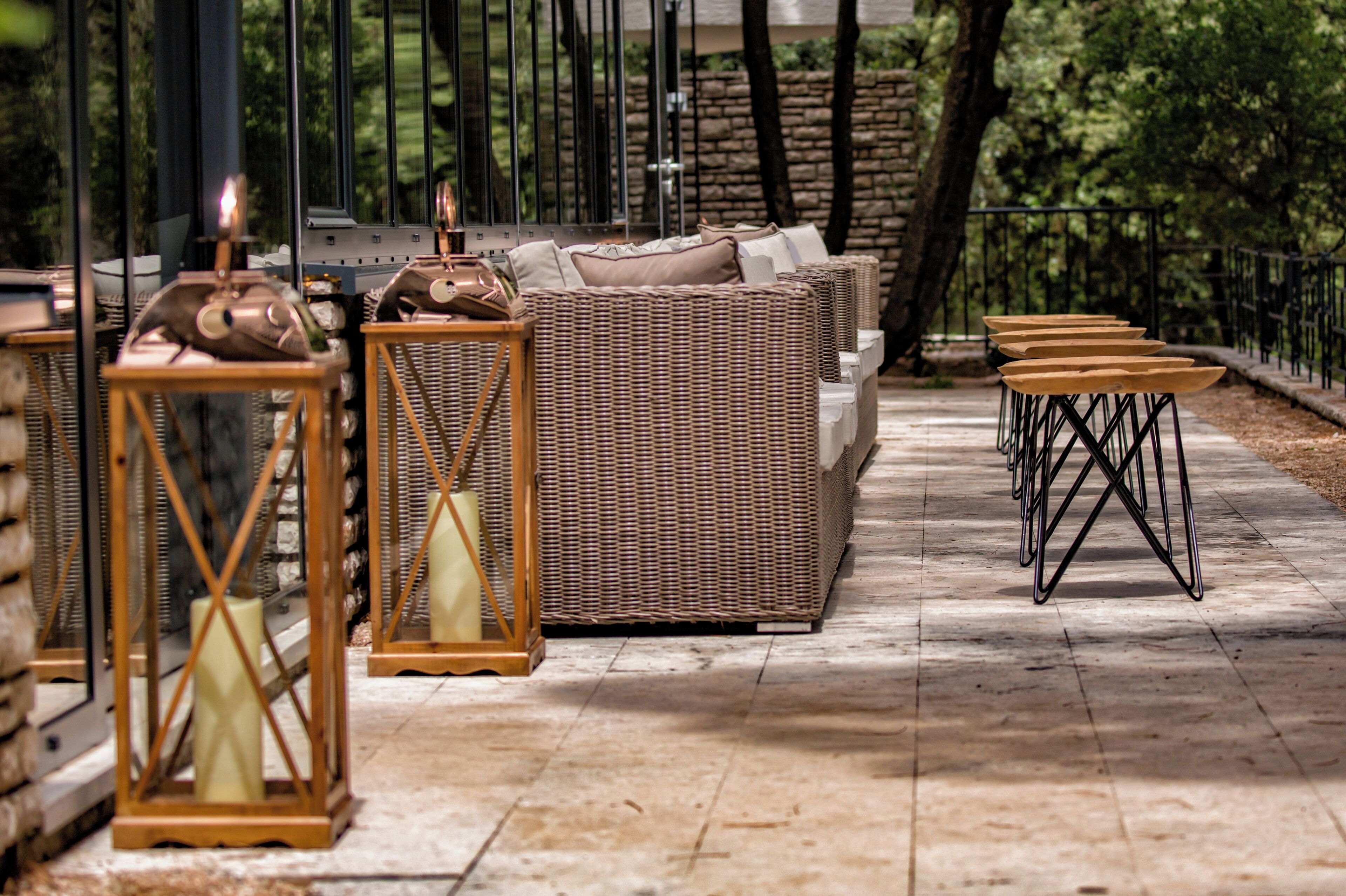 Un patio con mobiliario de mimbre, mesas de madera y faroles.