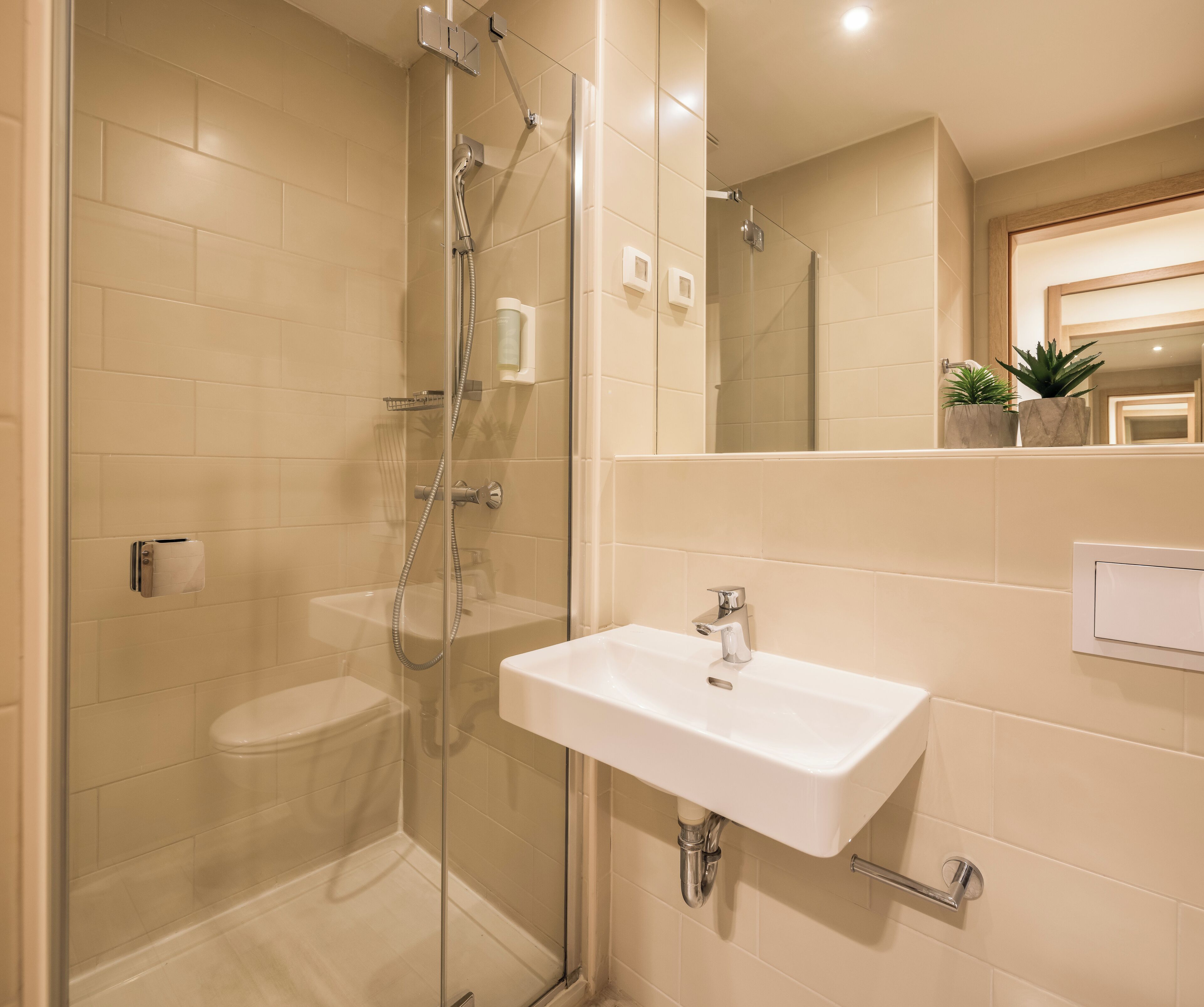 A modern bathroom with a glass-enclosed shower, a white sink, and a mirror above the sink.