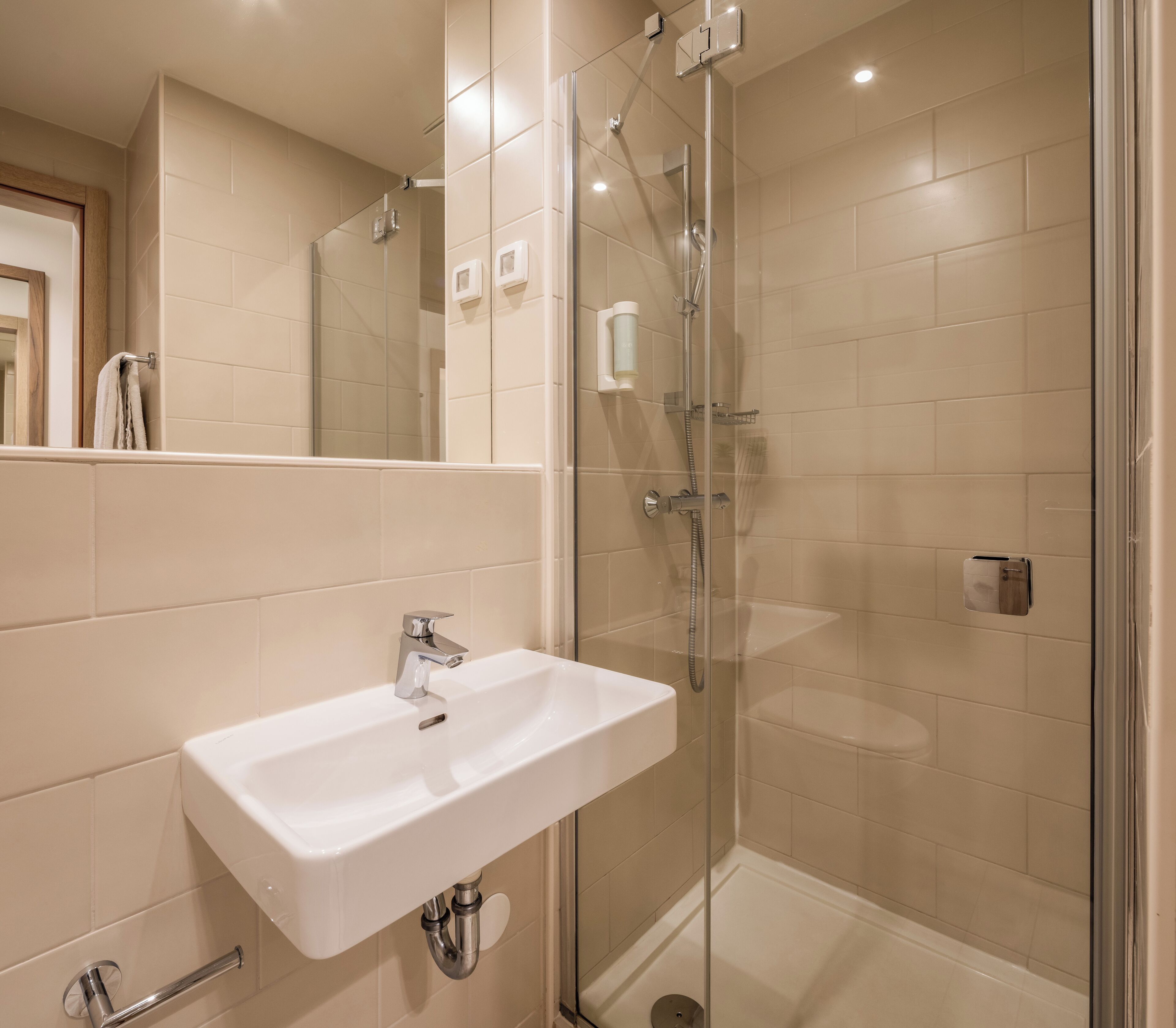 A modern bathroom with a glass-enclosed shower, a white sink, and a mirror.