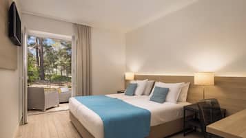 A hotel room with a bed, bedside tables, a TV, and a view of the outdoors.