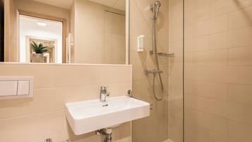 A bathroom with a white sink, a glass shower enclosure, and a mirror.