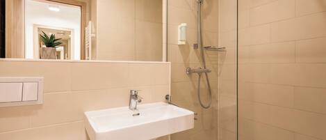 A bathroom with a white sink, a glass shower enclosure, and a mirror.