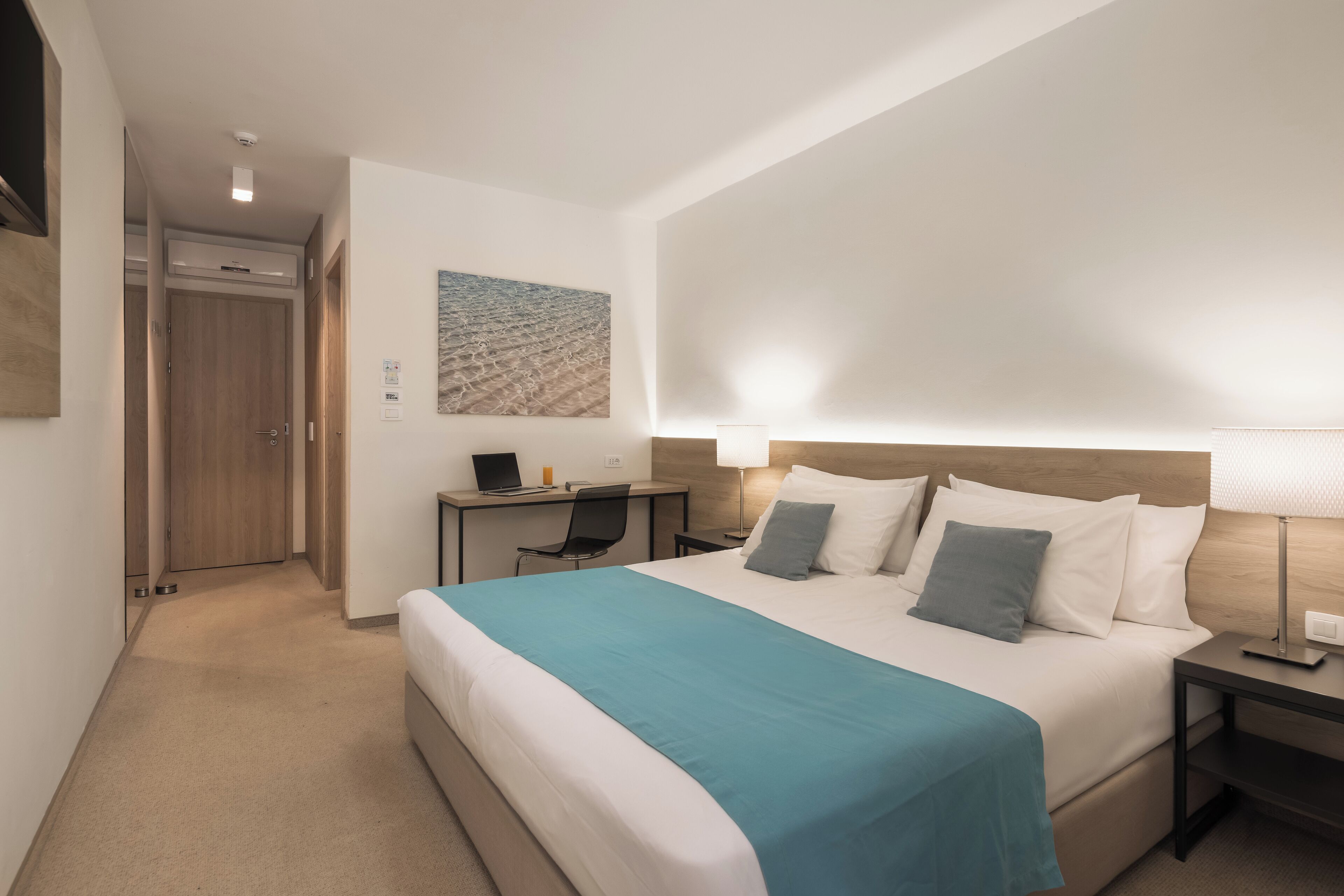 Une chambre d’hôtel comprenant un lit, une table de chevet, un bureau et une chaise.