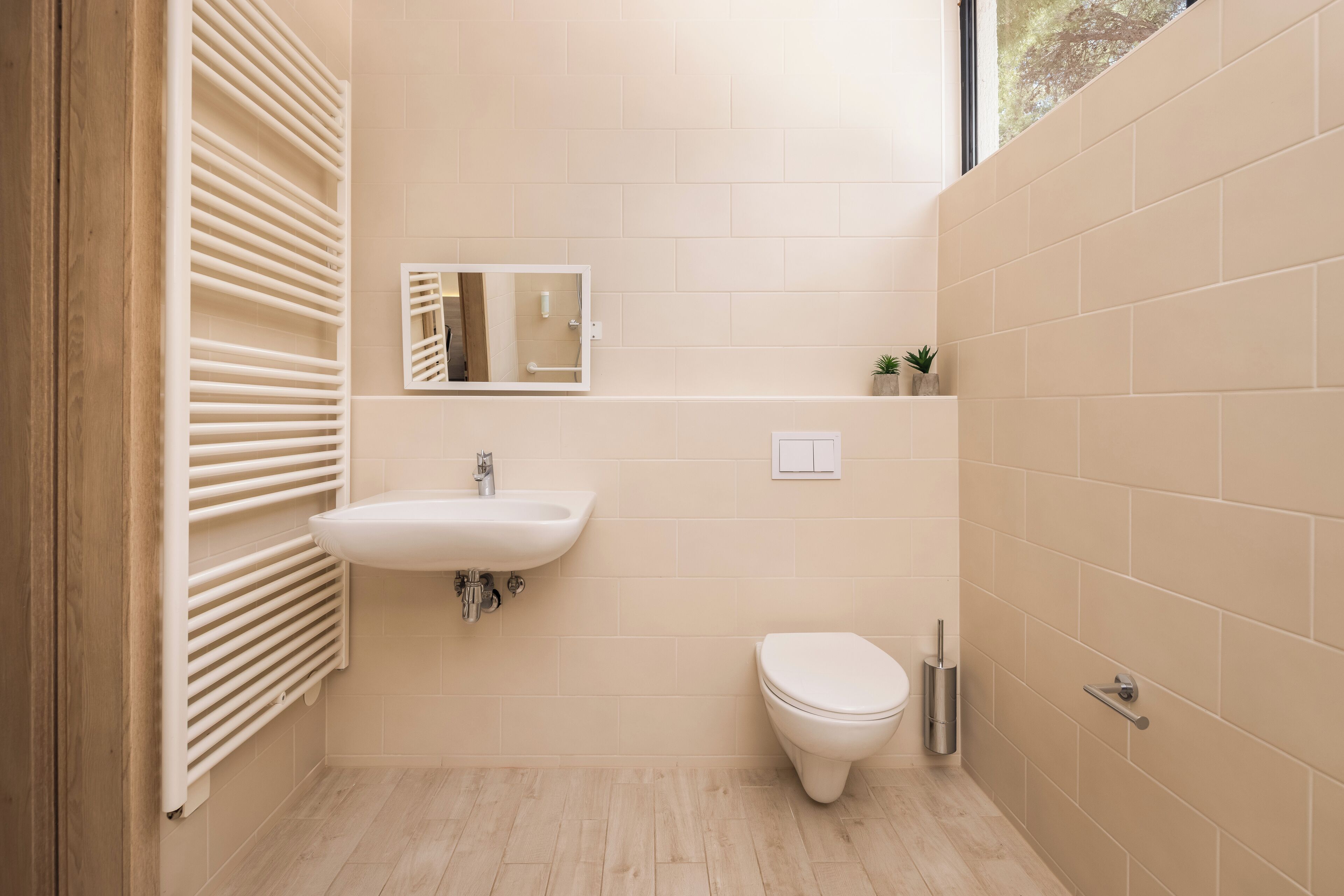 Un baño moderno con un lavamanos blanco, un inodoro y un espejo.