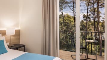 A hotel room with a bed, a nightstand, a lamp, and a balcony with a table and chair.