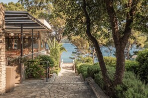 A stone staircase leading to a terrace with outdoor seating overlooking a body of water.
