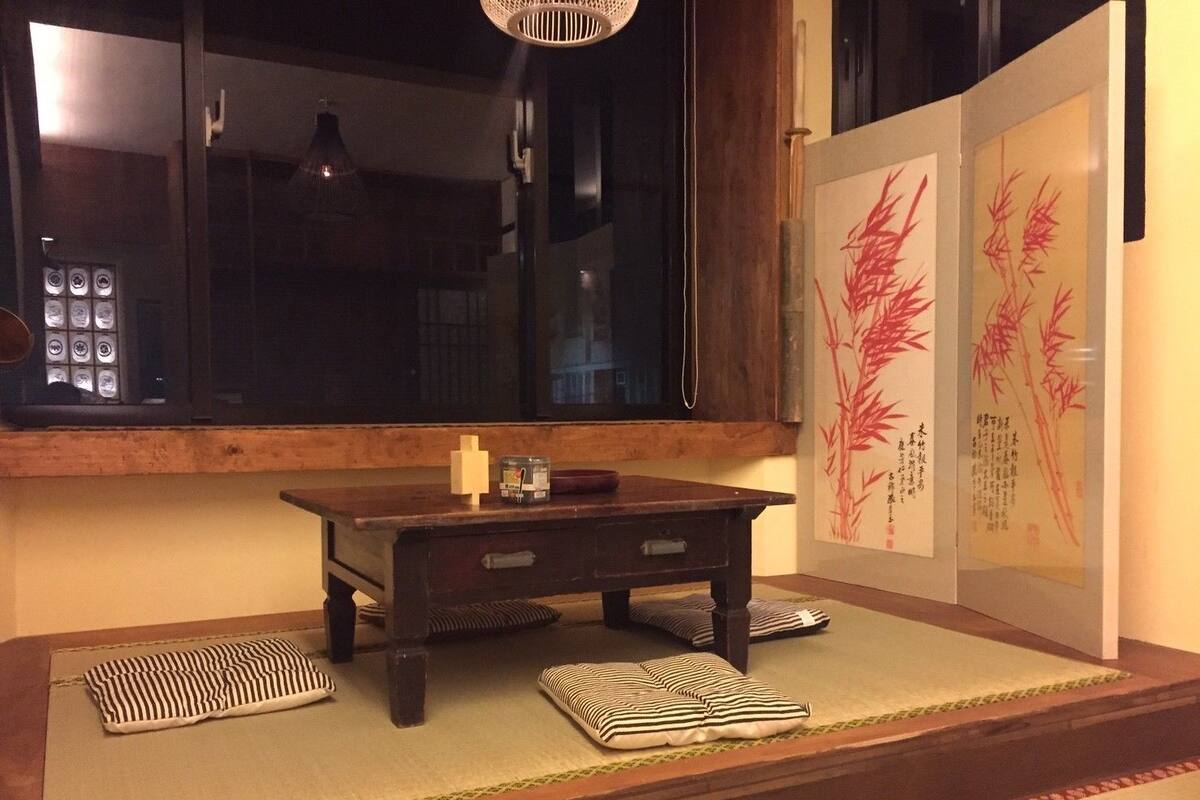 A traditional Japanese room with tatami flooring, a small wooden table, and a window with a view.