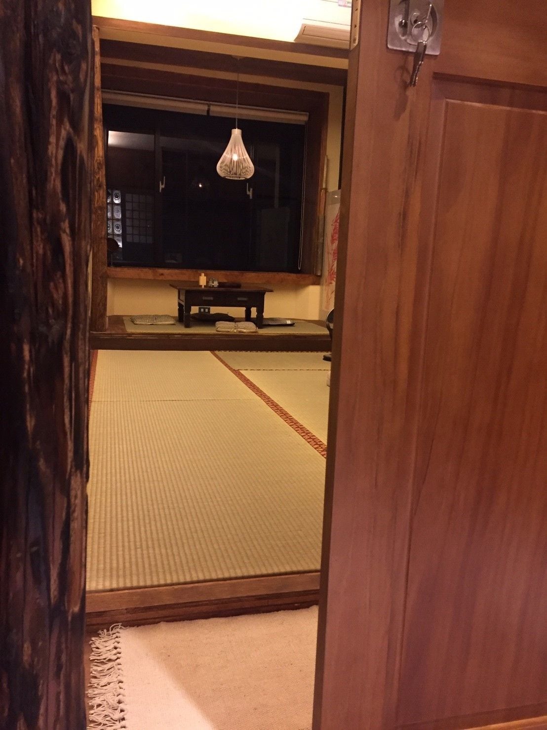 A traditional Japanese room with tatami flooring, a shoji screen, a hanging lamp, and a wooden cabinet.