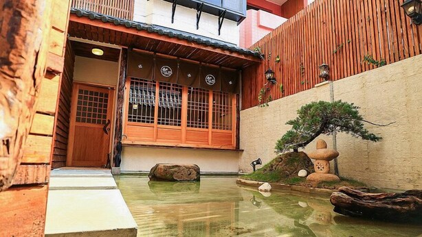 A traditional Japanese garden with a wooden building, a koi pond, and a bonsai tree. - Sunshiny Castle (Tainan)