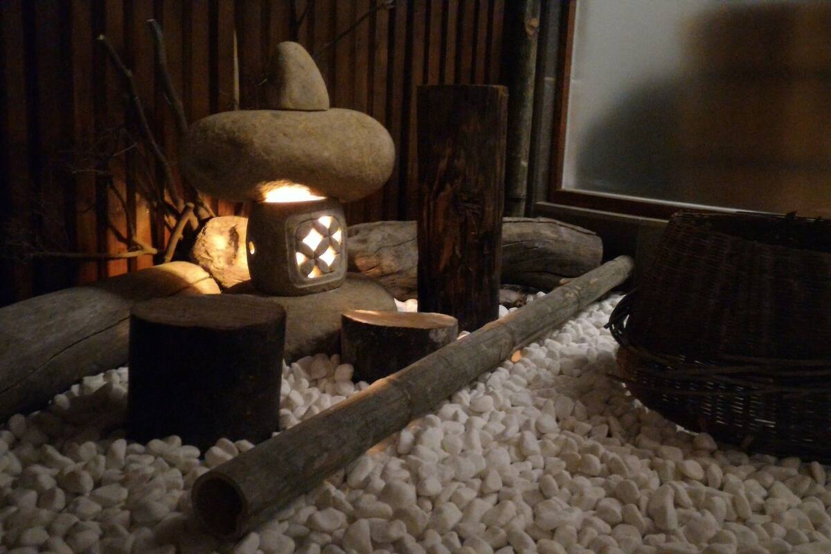 A rustic interior with a stone lantern, wooden logs, and a woven basket.