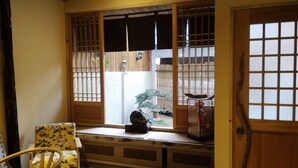 A traditional Japanese room with tatami flooring, a wooden sliding door, and a window with a view of a bamboo fence. - Sunshiny Castle (Tainan)