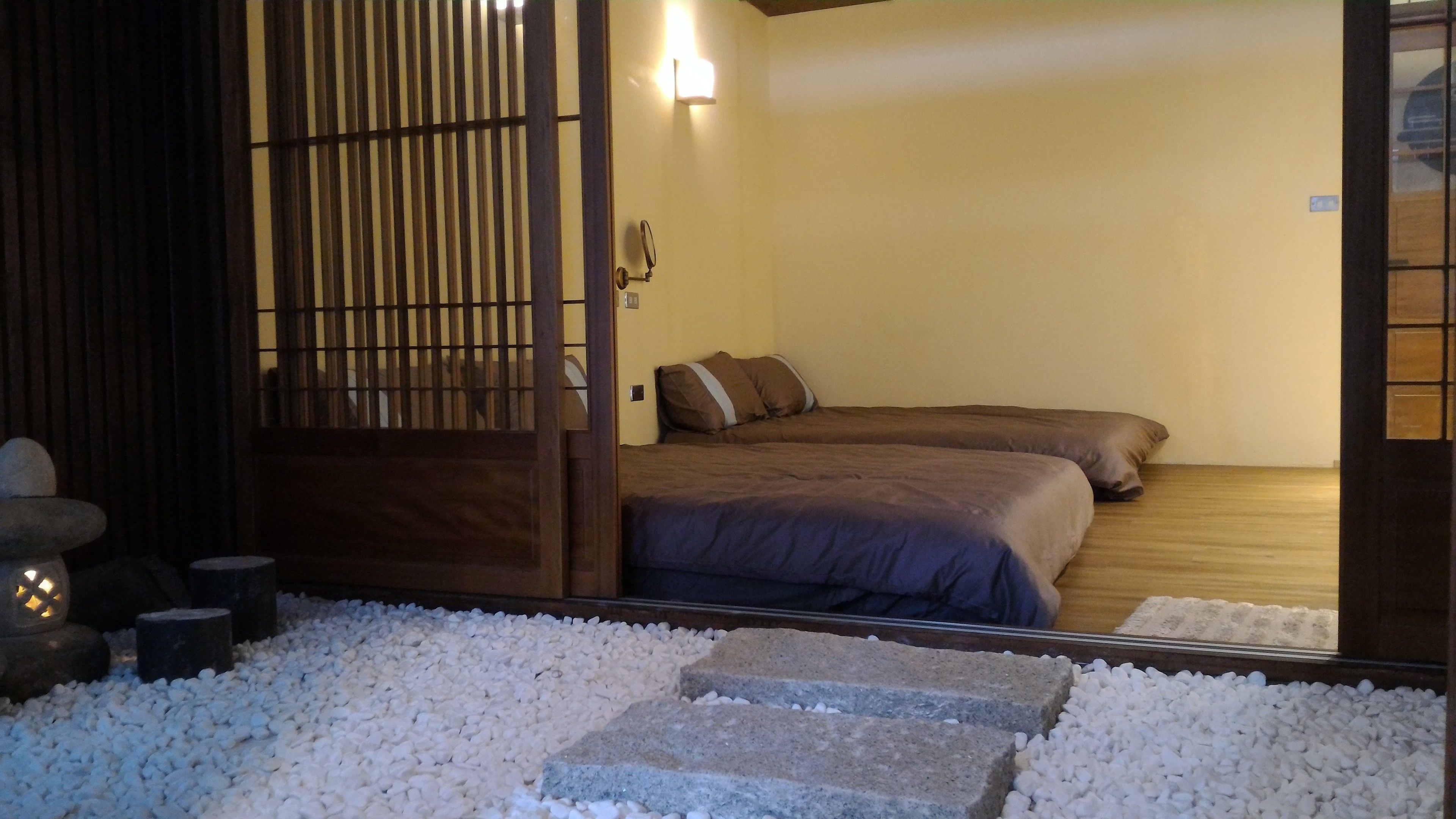 Una habitación tradicional japonesa con suelo de tatami, un puertas correderas shoji y una cama con dos almohadas.