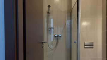 A modern bathroom with a glass-enclosed shower, a toilet, and a towel rack.