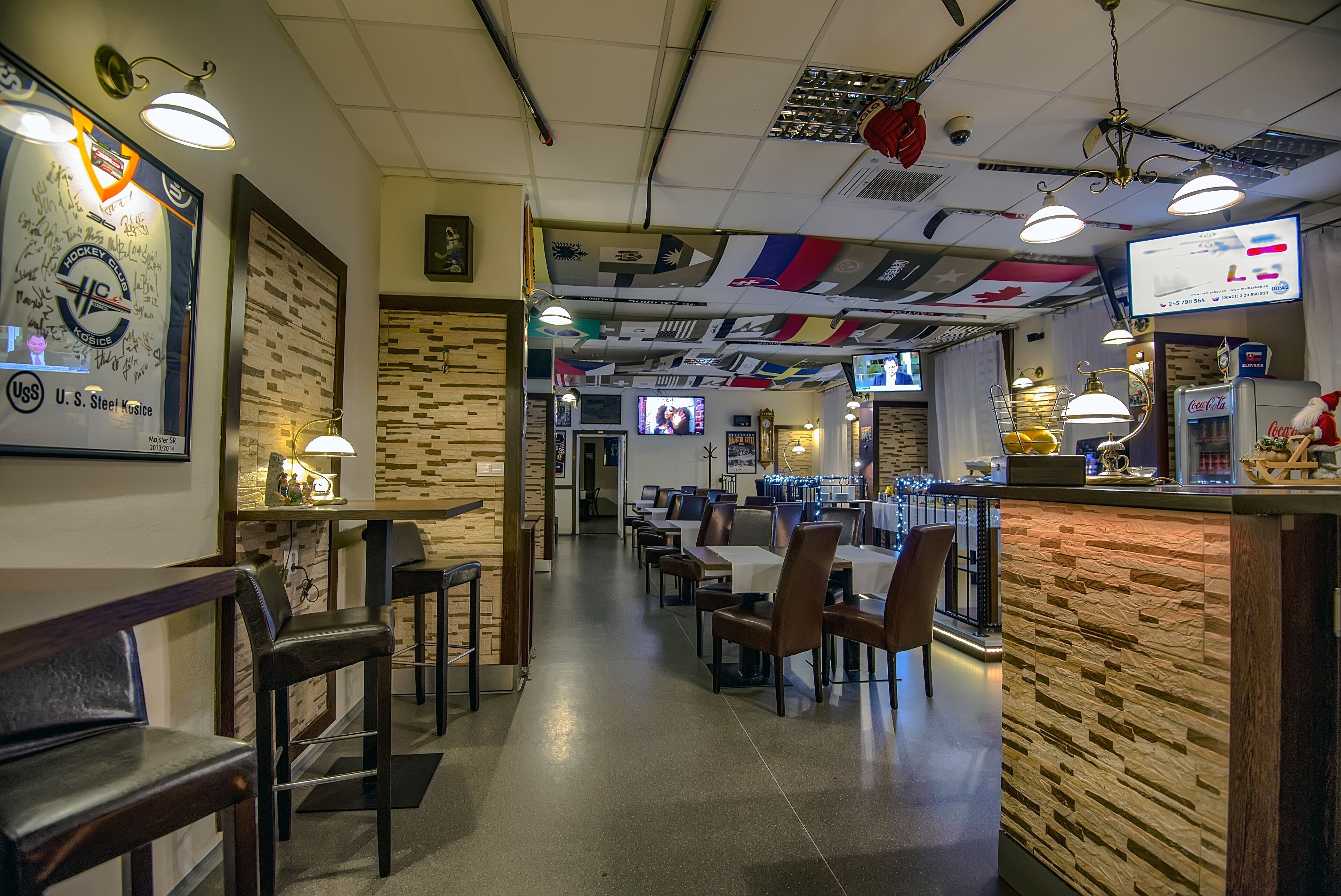 A restaurant interior with a long counter, multiple tables, and chairs.