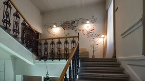 A staircase with a world map mural, a wooden handrail, and decorative metal railings. - Penzión Sport (Kosice)