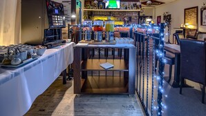 A bar area with a coffee machine, multiple beverage dispensers, and a television screen. - Penzión Sport (Kosice)