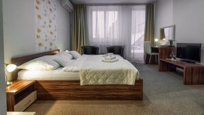 A hotel room with a large bed, a desk with a TV, a chair, and a desk lamp. - Penzión Sport (Kosice)