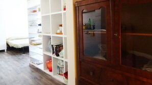 A room with a wooden wardrobe, white shelving units, and a bed. - Victoria Hotels Royal Garden (Como)