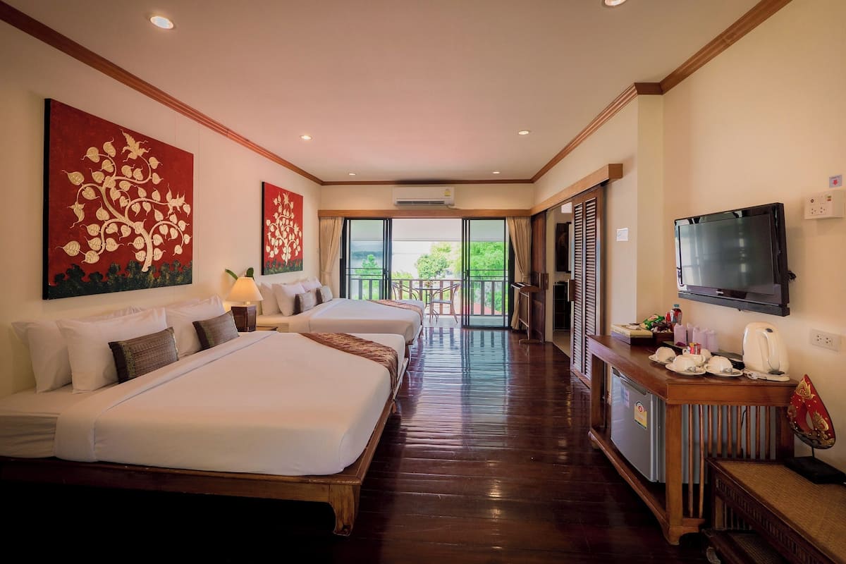 A hotel room with two beds, a TV, a coffee maker, and a balcony with a view.