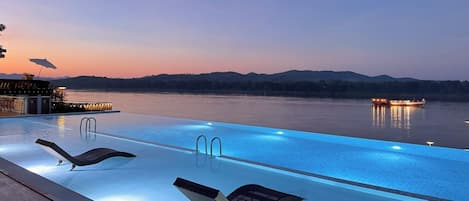 Una piscina al aire libre, sombrillas, sillones reclinables de piscina