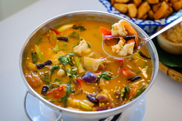 Un tazón de sopa con diferentes verduras y camarones.