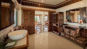 Un baño amplio con un lavabo blanco grande, armarios de madera y un espejo.