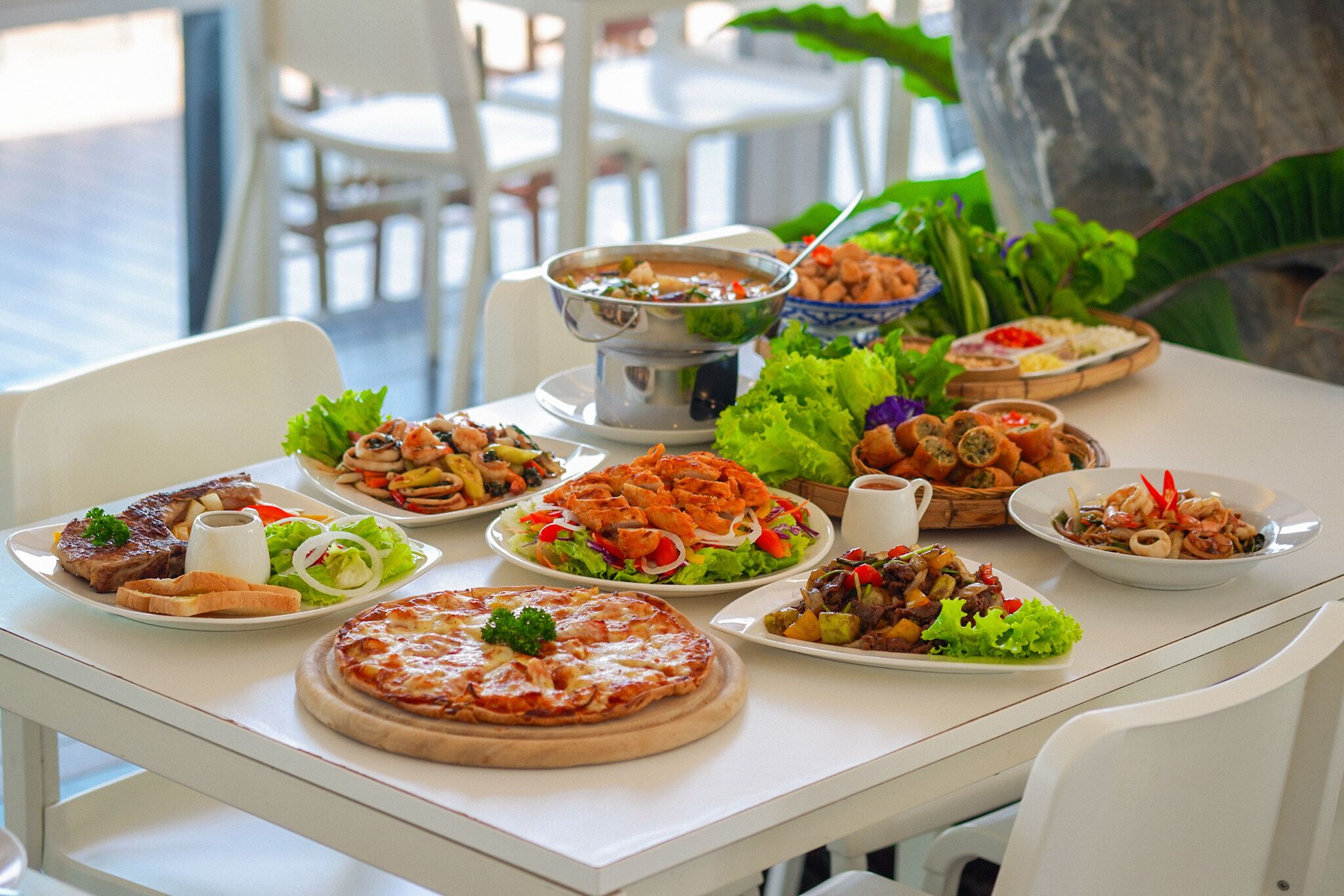 A table with various dishes including pizza, salads, and seafood.