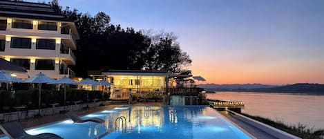 Una piscina al aire libre, sombrillas, sillones reclinables de piscina