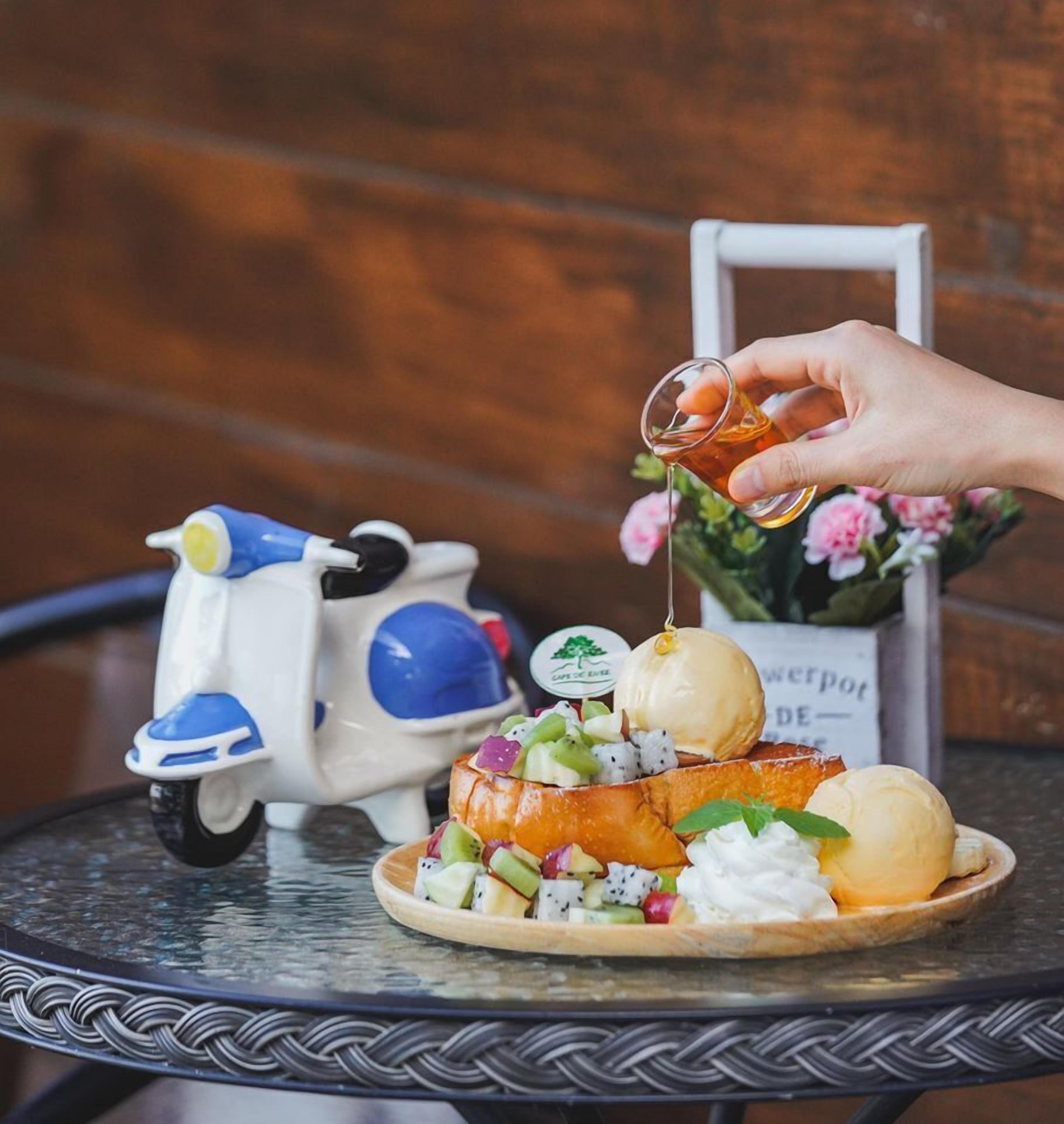 A hand pouring a drink onto a fruit and cheese platter on a table.