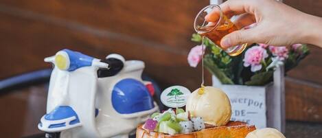 A hand pouring a drink onto a fruit and cheese platter on a table.