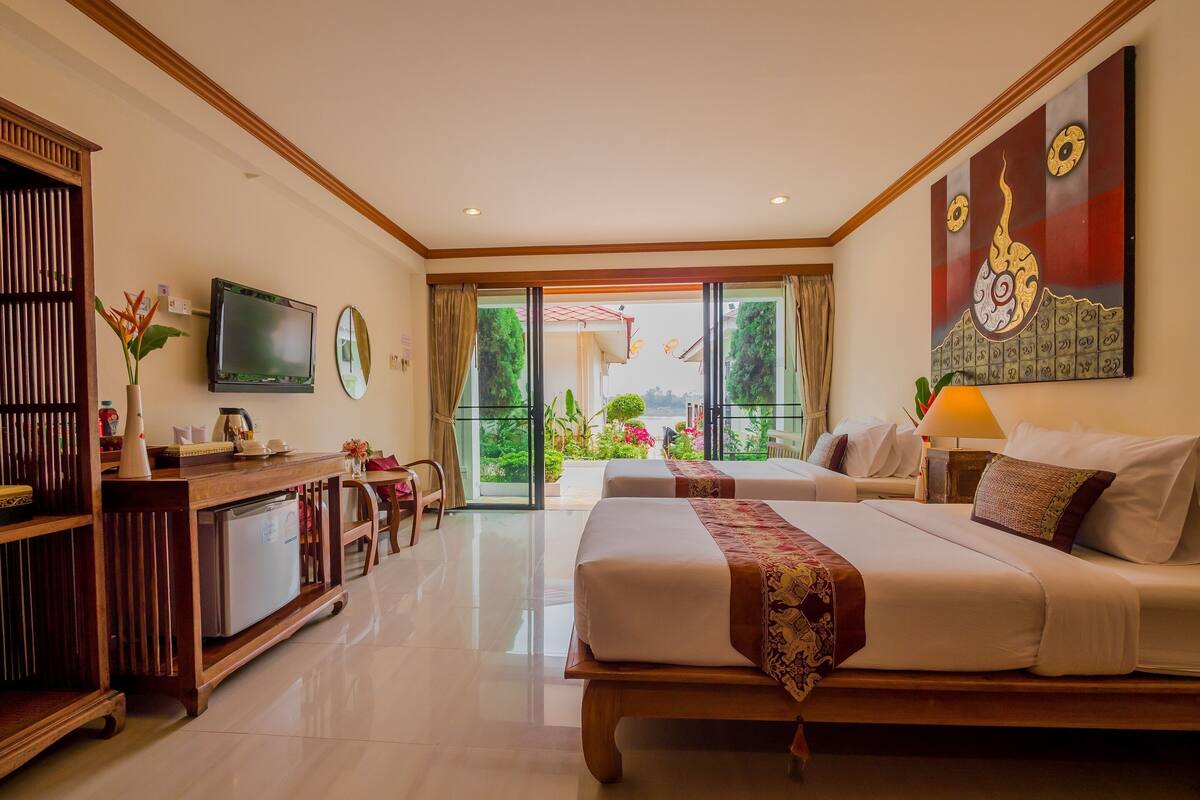 A hotel room with a bed, a desk, a television, and a view of the outdoors.