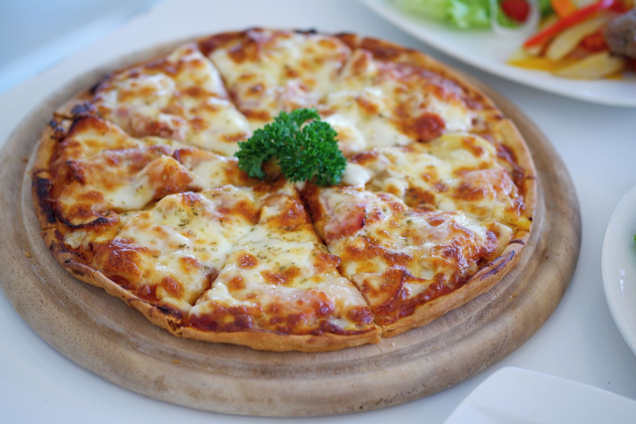 A pizza with a garnish on a wooden board.