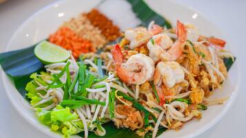 Un plato de pad thai con camarones, brotes de soja y lima.