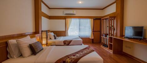 A hotel room with two beds, a TV, a wardrobe, and an air conditioning unit.