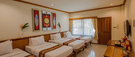 A hotel room with four single beds, a wooden desk, a television, and decorative wall art.