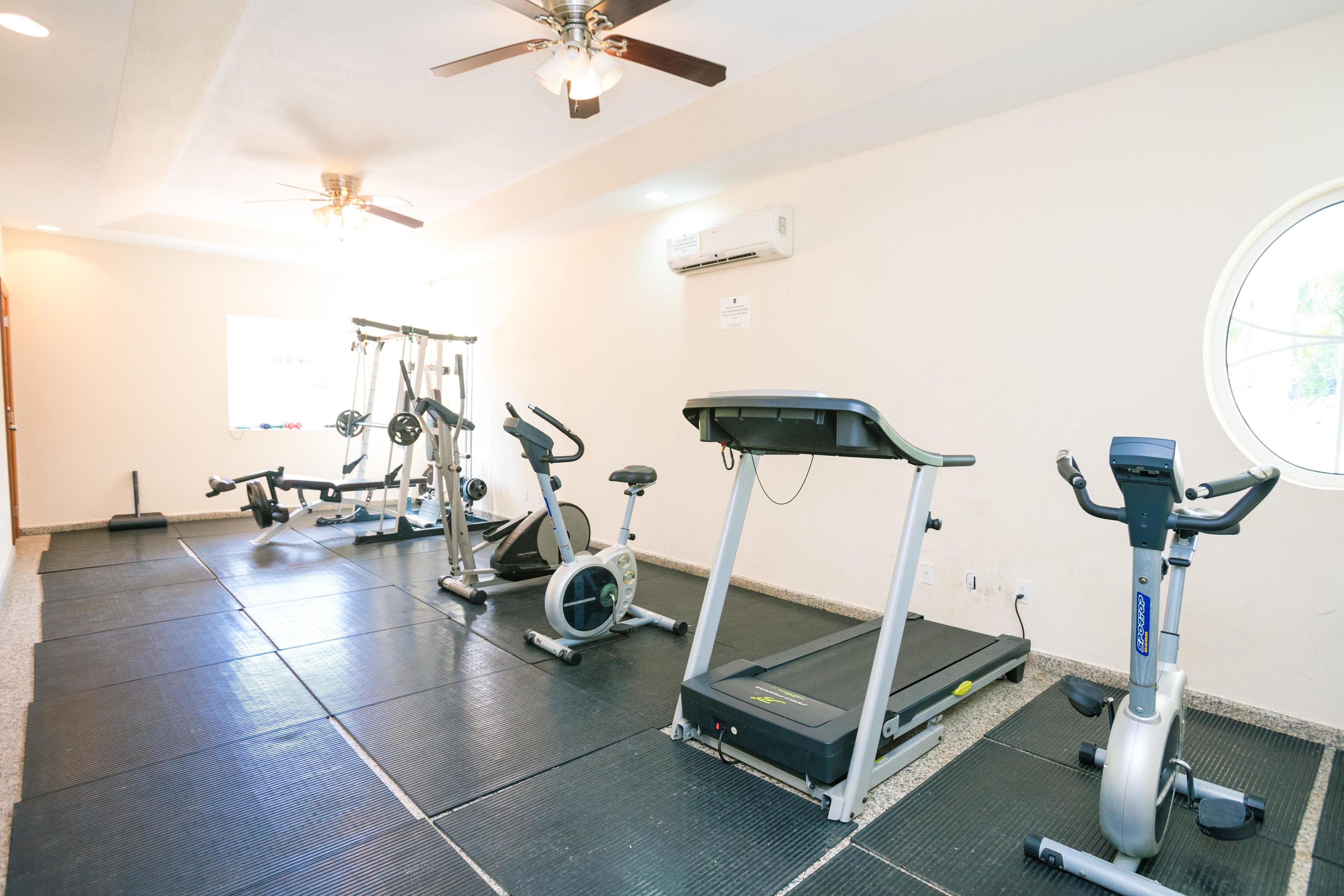 Uma academia com esteiras, bicicletas ergométricas e aparelhos de musculação.