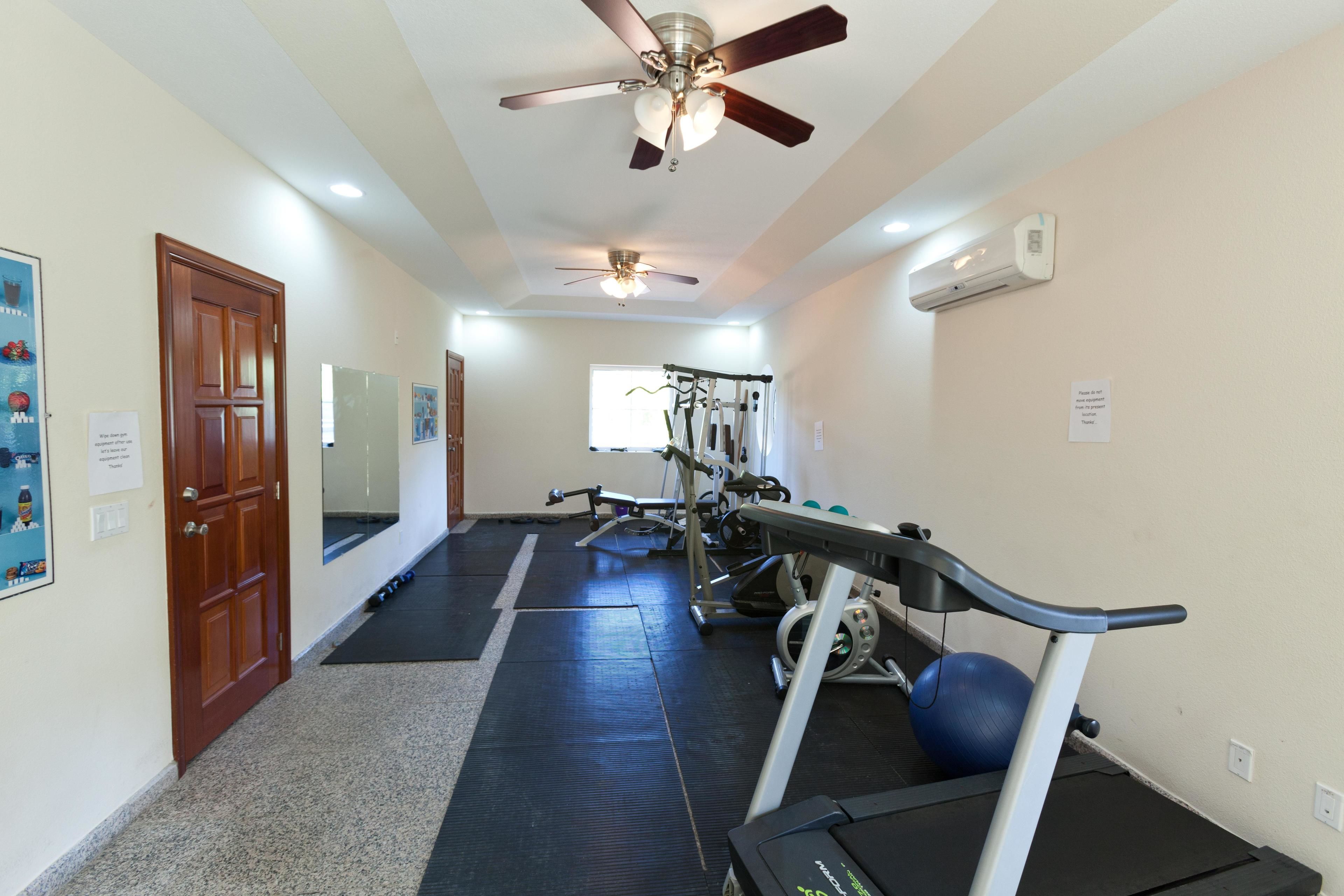 A home gym with exercise equipment, a ceiling fan, and a treadmill.