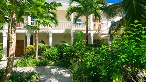 A courtyard with a palm tree, a building with a balcony, and a door. - Lawson Rock Parrotfish 206 (Roatan)