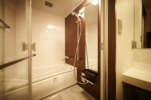 A modern bathroom with a glass shower enclosure, a white bathtub, and a wooden vanity. - Okayama Square Hotel Plus (Okayama)