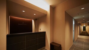 Zona de recepción de un hotel con diseño moderno, que incluye un mostrador de recepción y un pasillo que da a otras habitaciones.
